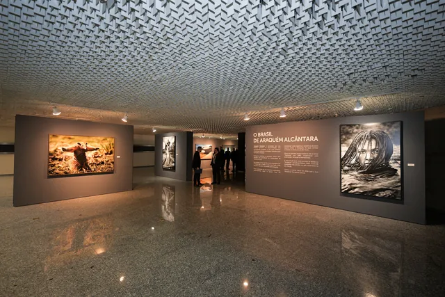 Vista da galeria, com grandes impressões e a parede de abertura ao fundo.